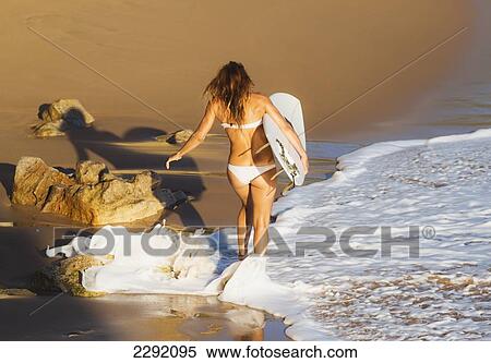 Stock Photography - Spain, Andalusia, Cadiz Province, Tarifa, Woman walking along beach with surfboard. Fotosearch