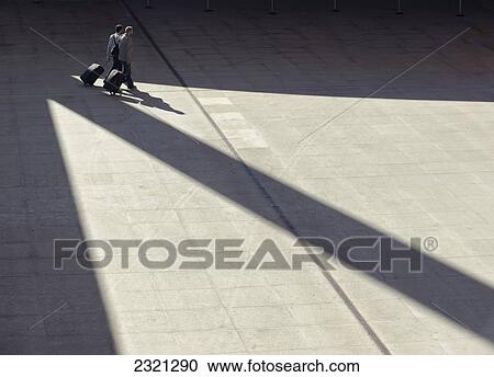 Stock Image - Spain, Andalusia, Malaga, Men Walking with luggage. Fotosearch