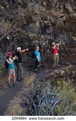 Picture - Spain, Canary Islands, Island of La Gomera, Tourists looking at Lo del Gato in Barranco de Benchijigua in Integral Nature Reserve; Santiago Ravine. Fotosearch