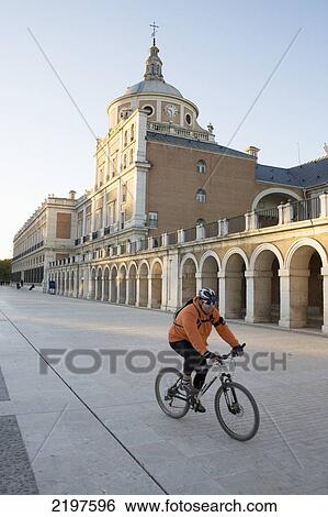 Stock Photograph - Spain, Cyclist Passing Palacio Real; Aranjuez. Fotosearch