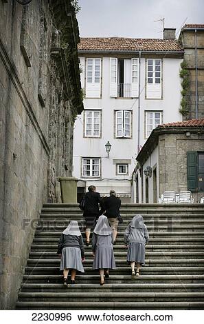 Stock Photograph - Spain, Galicia, Catholic Nuns Walking Past Cathedral; Santiago De Compostela. Fotosearch
