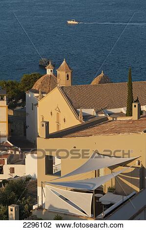 Stock Image - Spain, Ibiza, Looking over shaded roof terrace and Santo Domingo church in Dalt Vila; Ibiza Town. Fotosearch