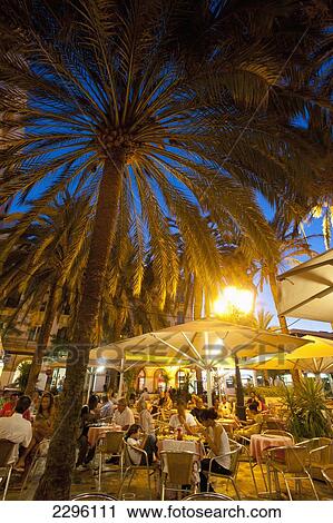Stock Image - Spain, Ibiza, People in cafe at dusk; Ibiza Town. Fotosearch