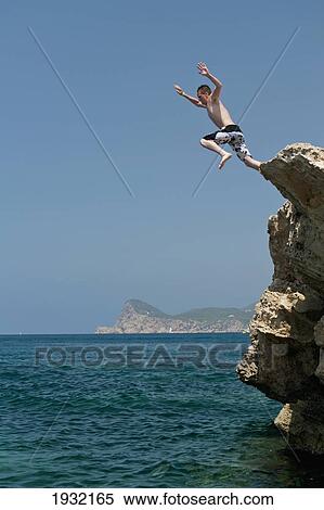 Spain, La Basse Beach; Ibiza, Man jumping from cliff View Large Photo Image Stock Photography - Spain, La Basse Beach; Ibiza, Man jumping from cliff. Fotosearch