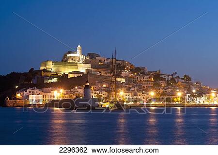 Stock Image - Spain, Looking across harbor to Ibiza town at dusk; Ibiza. Fotosearch