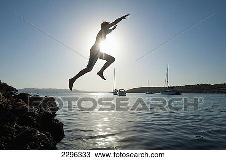 Spain, Man jumping off rocks into sea beside La Basse beach; Ibiza View Large Photo Image Stock Image - Spain, Man jumping off rocks into sea beside La Basse beach; Ibiza. Fotosearch