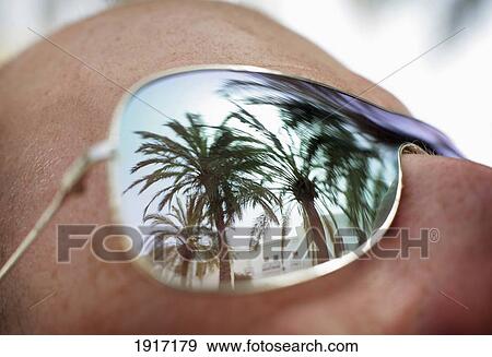 Stock Photo - Spain, Palm Trees Reflected in Man's Sunglasses; Costa de la Luz. Fotosearch