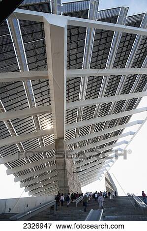 Stock Photo - Spain, Parc del Forum; Barcelona, Festival goers under a huge solar panel in Primavera Sound music festival. Fotosearch