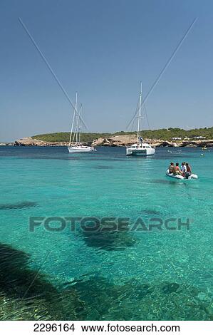 Picture - Spain, People in small boat going out to their yacht off La Basse beach; Ibiza. Fotosearch