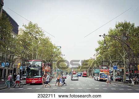 Stock Image - Spain, Street scene with people crossing busy road; Barcelona. Fotosearch