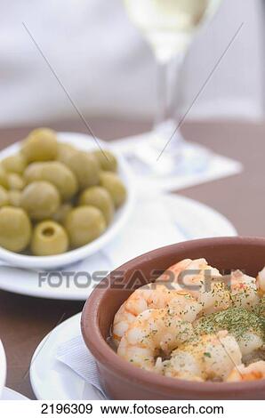 Stock Photo - Spain, Tapas (olives and prawns) with glass of wine; Barcelona. Fotosearch