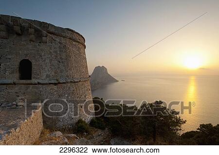 Stock Image - Spain, Torre des Savinar and Es Vedra island at sunset; Ibiza. Fotosearch