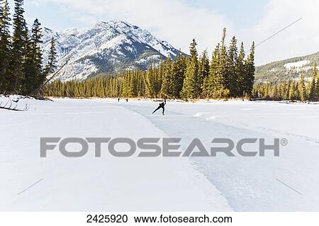 Stock Image - Speed skater practicing on Bow River near Banff; Alberta, Canada. Fotosearch