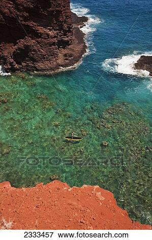 Stock Photo - Stand-up paddleboarding at Pu'u Pehe rock, (sweetheart rock); Lanai, Hawaii, United States of America. Fotosearch