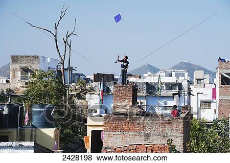 Standing on a brick rooftop flying a kite; Udaipur, India View Large Photo Image Stock Photo - Standing on a brick rooftop flying a kite; Udaipur, India. Fotosearch