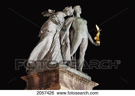 Stock Photograph - Statue Of A Man With A Scythe And A Woman Sowing Seed Representing Labor And Wealth On Heroes' Square At Night, Budapest, Hungary. Fotosearch
