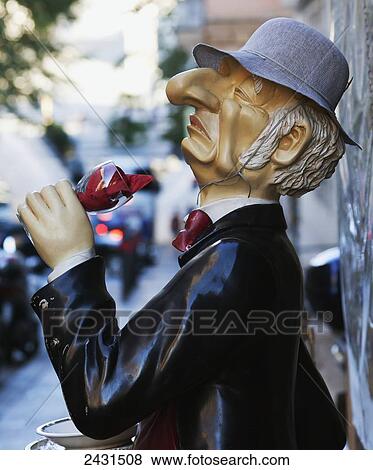 Statue of an elderly man holding a glass of red wine outside a building along a street View Large Photo Image Stock Photo - Statue of an elderly man holding a glass of red wine outside a building along a street. Fotosearch