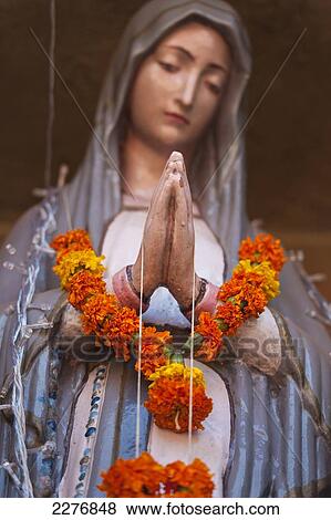 Stock Photo - Statue of the Virgin Mary with garland of marigolds around her neck; Goa, India. Fotosearch