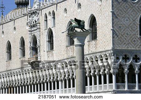 Stock Image - Statue on top of a column and a building with ornate facade in the background; Venice, Italy. Fotosearch