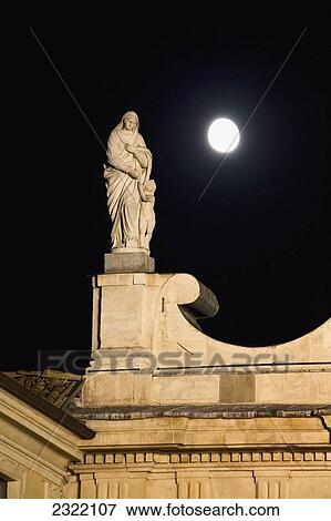 Stock Photo - Statue on top of church with full moon; Parma, Emilia-Romagna, Italy. Fotosearch