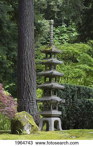 Stock Image - Stone Lantern With Trees And Bushes In The Background; Portland Oregon United States Of America. Fotosearch