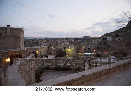 Stock Image - Stone Walls Inside A Community Of Houses With Lights At Dusk; Nevsehir Turkey. Fotosearch