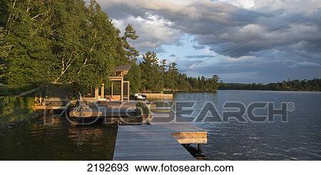 Stock Image - Storm Clouds Over A Lake With Wooden Docks; Lake Of The Woods Ontario Canada. Fotosearch