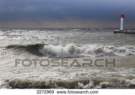 Storm waves crashing on a beach near a lighthouse on lake ontario; whitby ontario canada View Large Photo Image Stock Photo - Storm waves crashing on a beach near a lighthouse on lake ontario; whitby ontario canada. Fotosearch