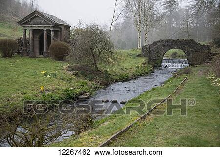 Stream flowing by bridge with ancient temple in garden setting; Devon, England View Large Photo Image Stock Image - Stream flowing by bridge with ancient temple in garden setting; Devon, England. Fotosearch