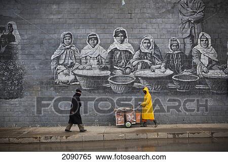Stock Photography - Street Cleaner In Front Of Mural Of Famous Kurdish People, Sulaymaniyah, Iraqi Kurdistan, Iraq. Fotosearch