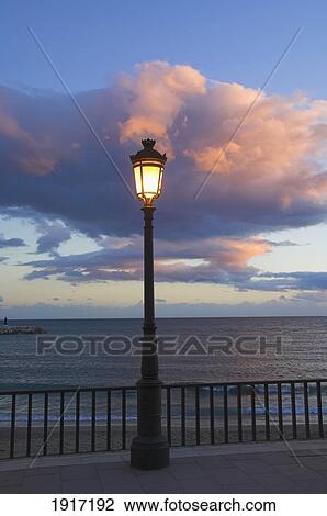 Stock Image - Street Lamp With Cloud Above And Sea Behind. Fotosearch
