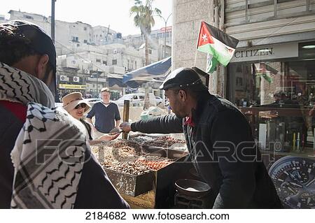 Stock Image - Street Nut Roasting Vendor Serving Tourists Warm Roasted Nuts, Amman, Jordan, Middle East. Fotosearch