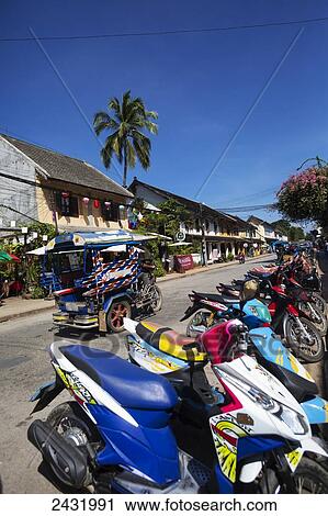 Stock Image - Street scene in Luang Prabang with motorcycles and Tuk Tuks; Luang Prabang, Louangphabang Province, Loas. Fotosearch