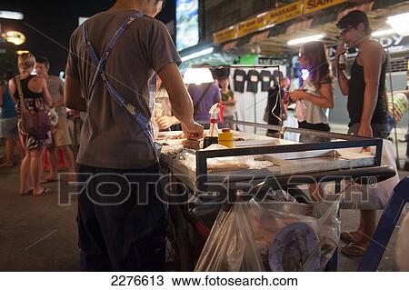 Stock Image - Street traders, locals and tourists mingle along the Khao San Road at night; Bangkok, Thailand. Fotosearch