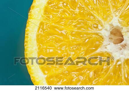 Stock Image - Studio shot of an orange half on a blue background.. Fotosearch