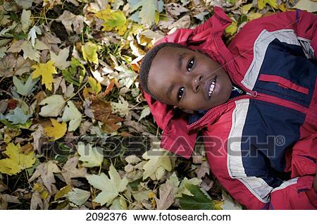 Sudanese Boy Lying In Autumn Leaves Outside Esl School; Guelph Ontario Canada View Large Photo Image Stock Photograph - Sudanese Boy Lying In Autumn Leaves Outside Esl School; Guelph Ontario Canada. Fotosearch
