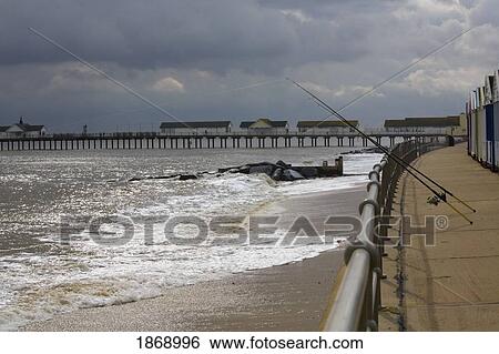 Stock Photograph - Suffolk, England; Fishing Rods Hanging Off The Pier On The Coast Of The North Sea. Fotosearch