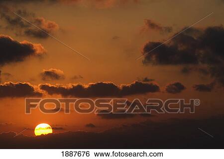 Stock Photograph - Sun And Clouds At Sunset In Orange Sky. Fotosearch