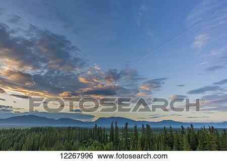 Stock Photograph - Sun has set over the Baird Mountains, forest and green tundra near the village of Shungnak, Arctic Alaska, summer. Fotosearch