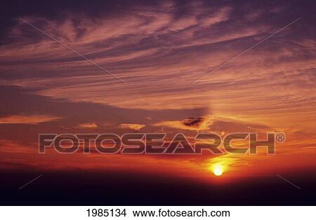 Sun Setting In Colorful Sky, Wispy Clouds. View Large Photo Image Picture - Sun Setting In Colorful Sky, Wispy Clouds.. Fotosearch