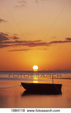 Stock Photo - Sun Setting Over Ocean, Boat Silhouetted Against Orange Sky.. Fotosearch