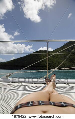 Stock Image - Sunbather In Bikini Sunbathing On Sailboat, Low Angle View. Fotosearch