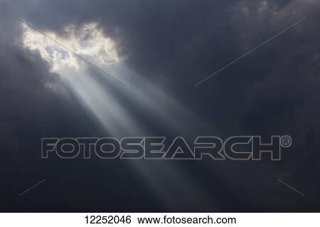 Stock Photograph - Sunlight breaking through dark storm clouds; Georgetown, Ontario, Canada. Fotosearch