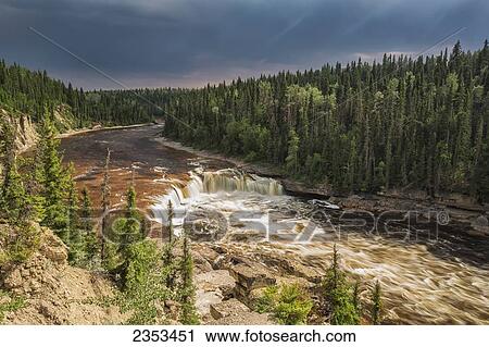 Stock Image - Sunlight Illuminates The Trout River Flows Over Coral Falls; Northwest Territories, Canada. Fotosearch