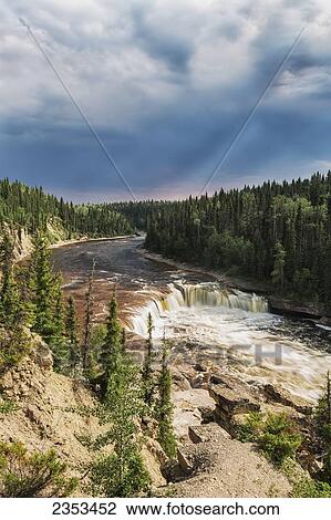 Stock Image - Sunlight Illuminates The Trout River Flows Over Coral Falls; Northwest Territories, Canada. Fotosearch