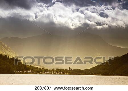 Stock Photo - Sunlight Shining Through The Clouds Into A Glowing Valley; Argyll Scotland. Fotosearch