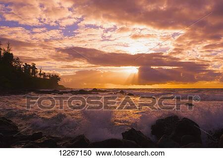 Stock Image - Sunrise and waves crashing on the rocks, Kealia Beach; Kauai, Hawaii, United States of America. Fotosearch