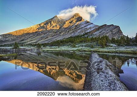Stock Image - Sunrise Over A Peak Reflected In A Tarn Below Baker Lake In The Skoki Wilderness In Banff National Park; Banff Alberta Canada. Fotosearch