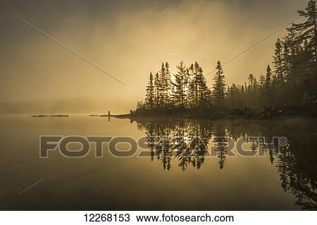 Stock Image - Sunrise over a tranquil lake; Ontario, Canada. Fotosearch