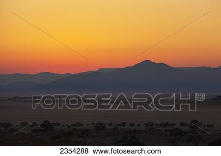 Stock Photo - Sunrise With A Silhouette Of The Landscape; Namibia. Fotosearch